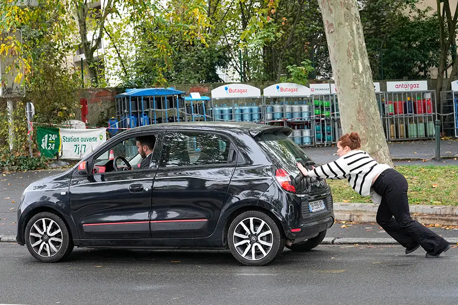 A French lady pushes her car.
